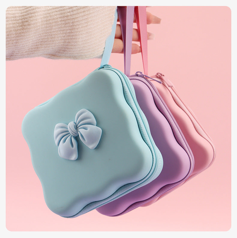 Blue, purple, and pink bow cable organizer pouches with wrist straps; each sold separately